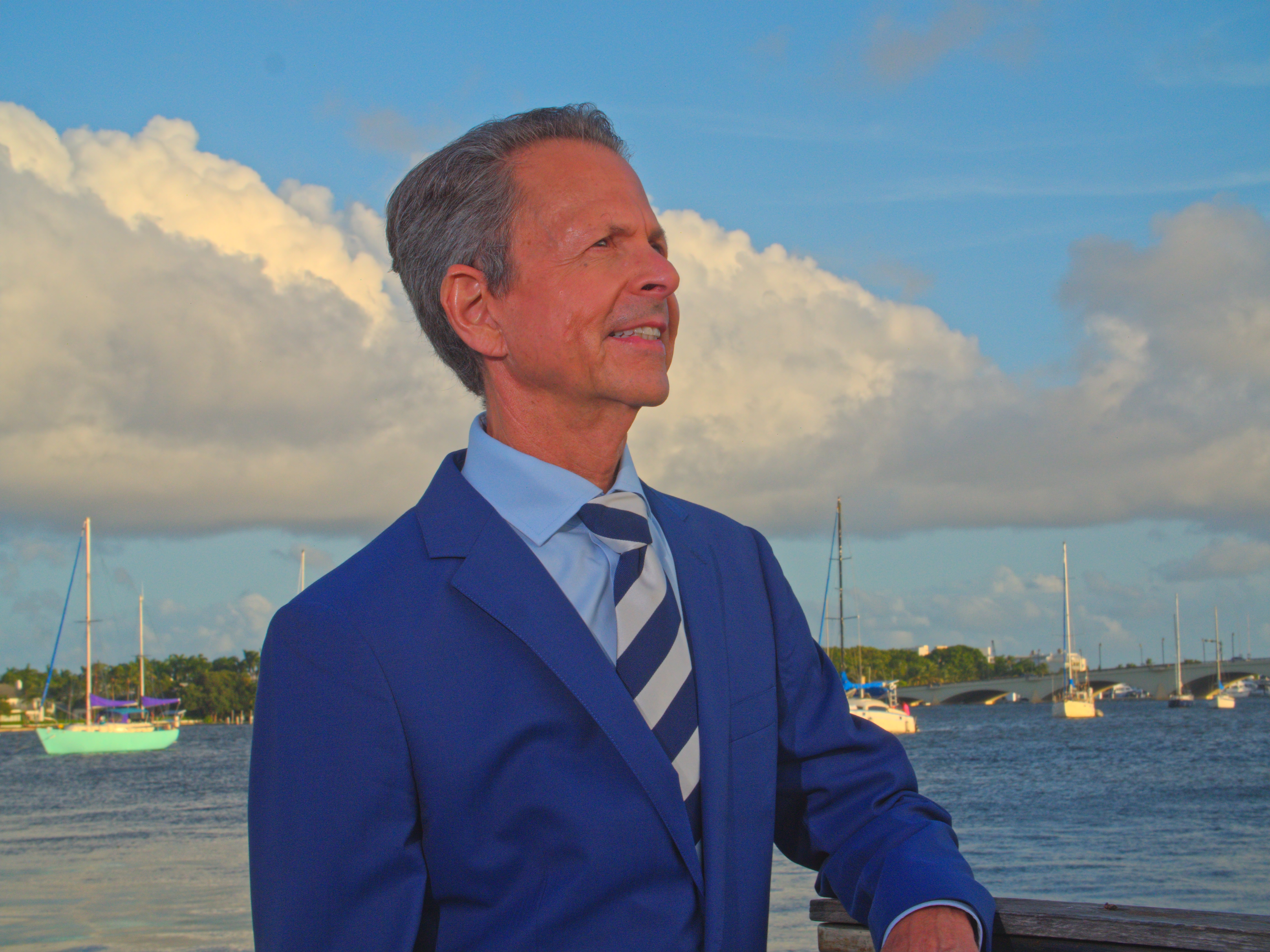 Gregg Weiss on a sailboat with the bridge behind him