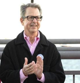 Gregg Weiss applauding at a waterfront gathering